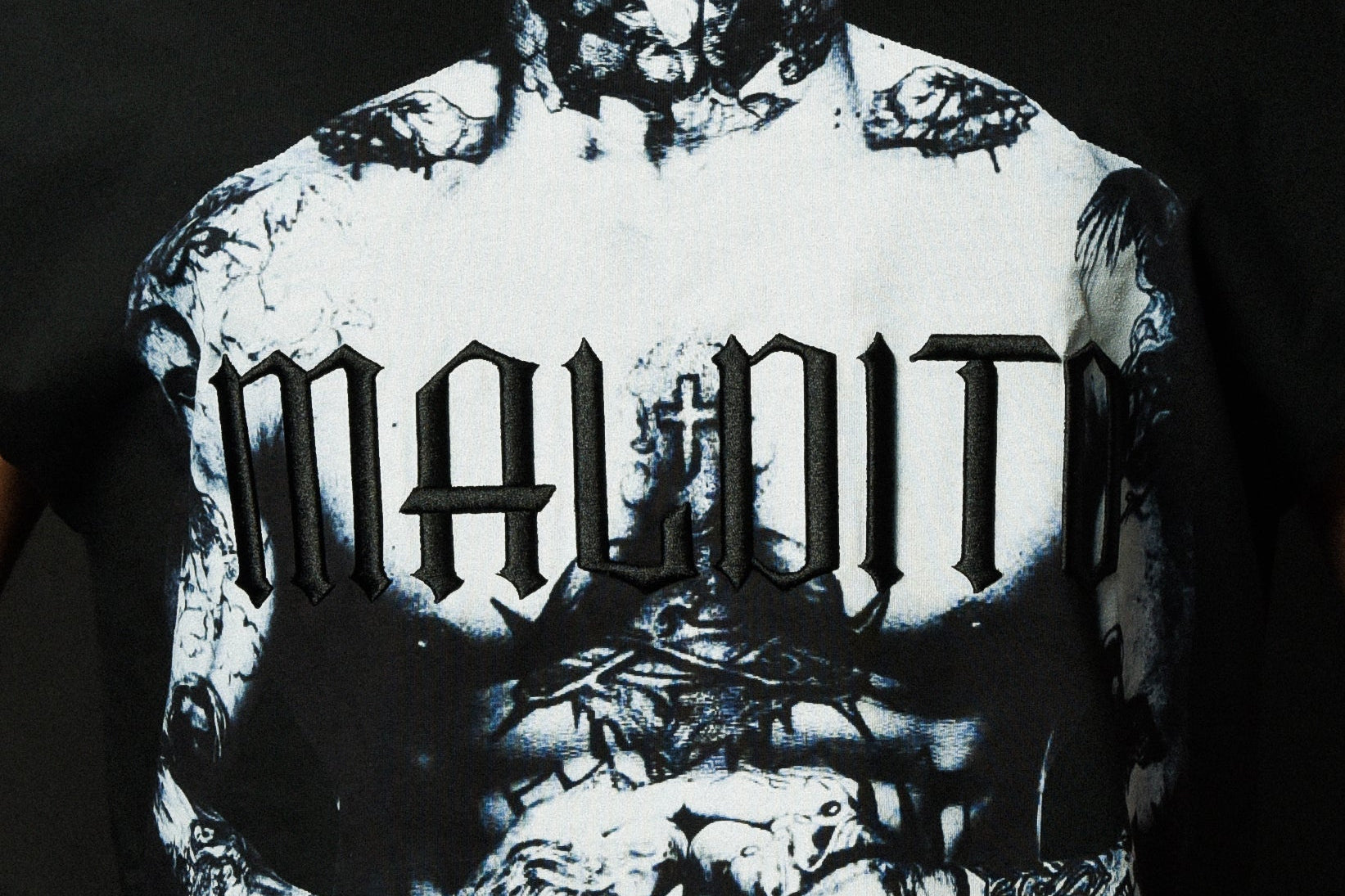 Close-up detail of the embroidery on the MALDITO cut-off tee showing texture and stitching.