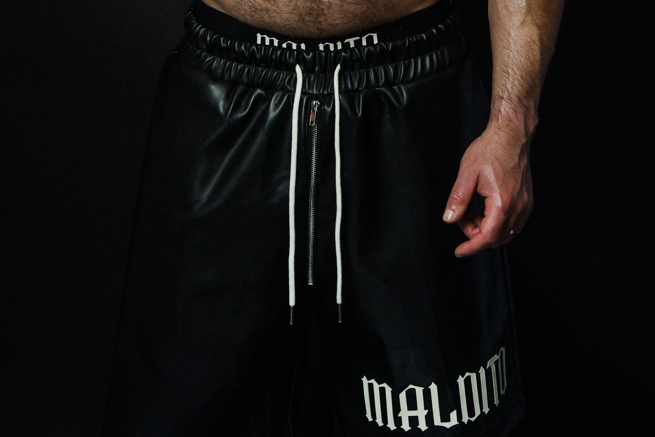 Close-up detail of the MALDITO black leather shorts showing the texture and construction.