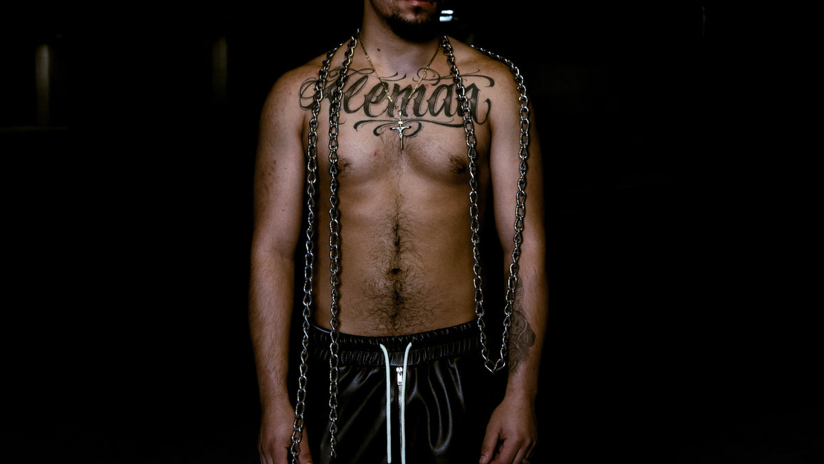 Close-up editorial image of a model’s torso with chains draped over the shoulders styled with MALDITO pieces